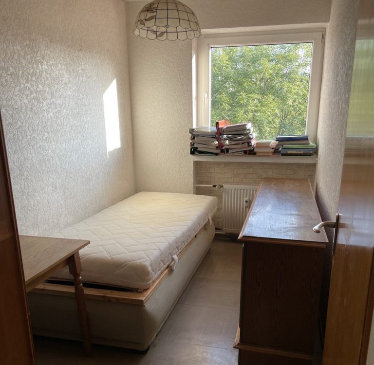 Das Bild zeigt ein Schlafzimmer mit einem Bett und einer Kommode
